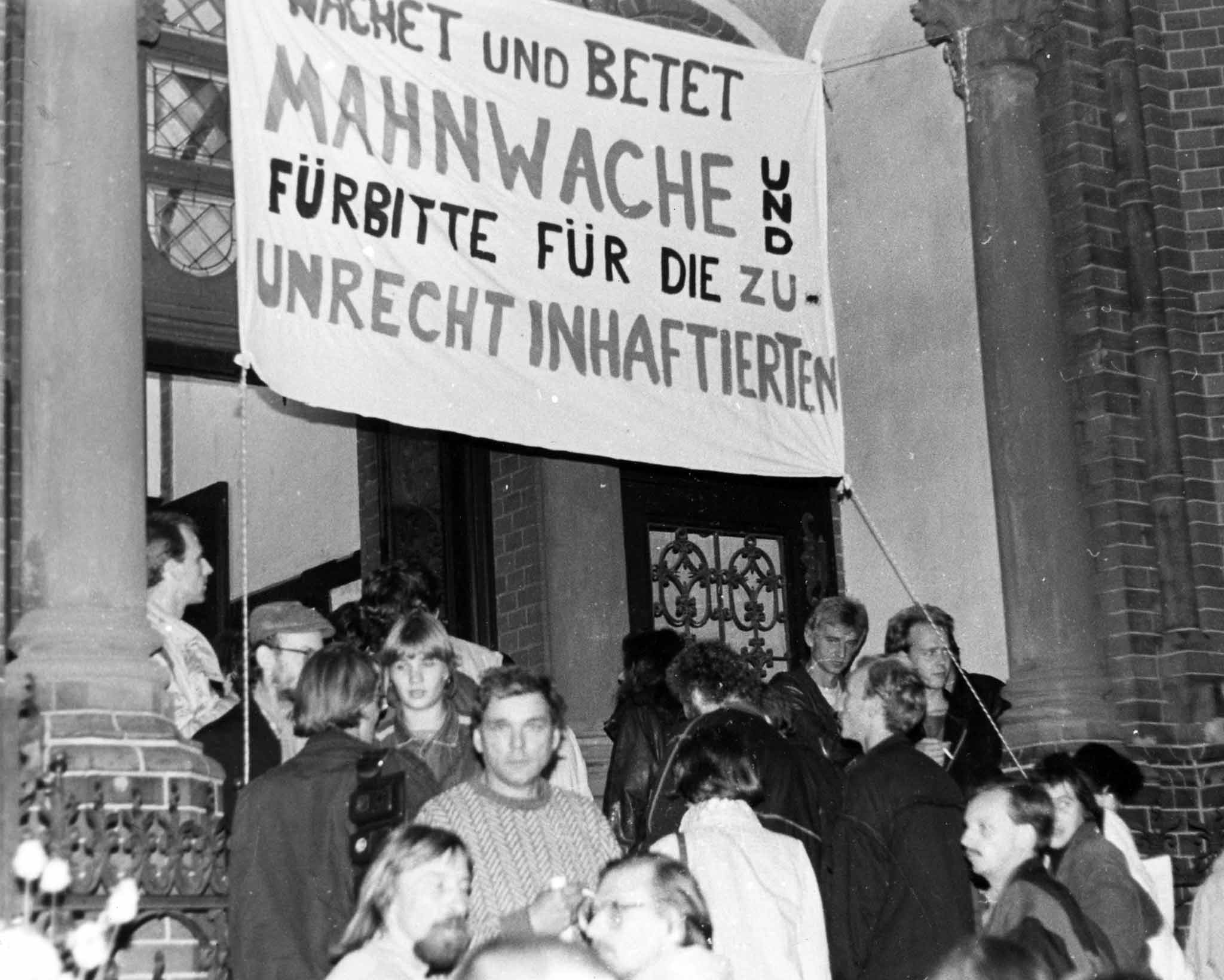 Schwarz-weiß-Foto von Menschen die einen Protesbanner in die Luft halten