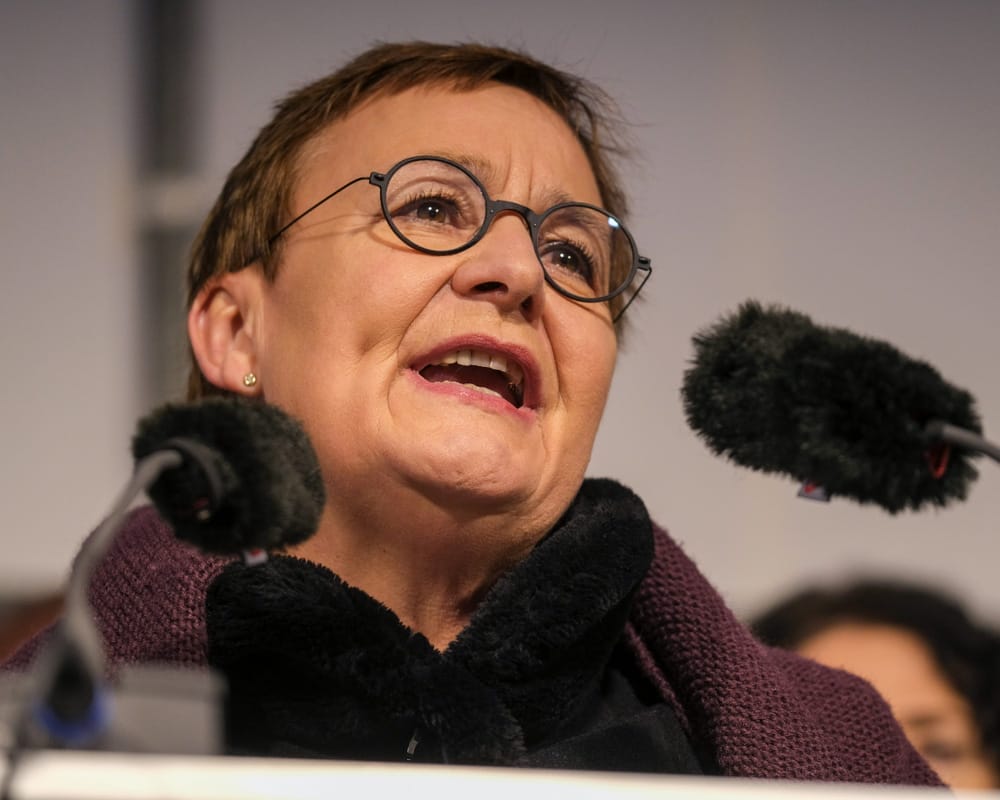 Frau mit Brille spricht in Podiumsmikrofon