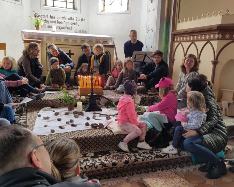 Eltern und Kinder sitzen vor einem Altar