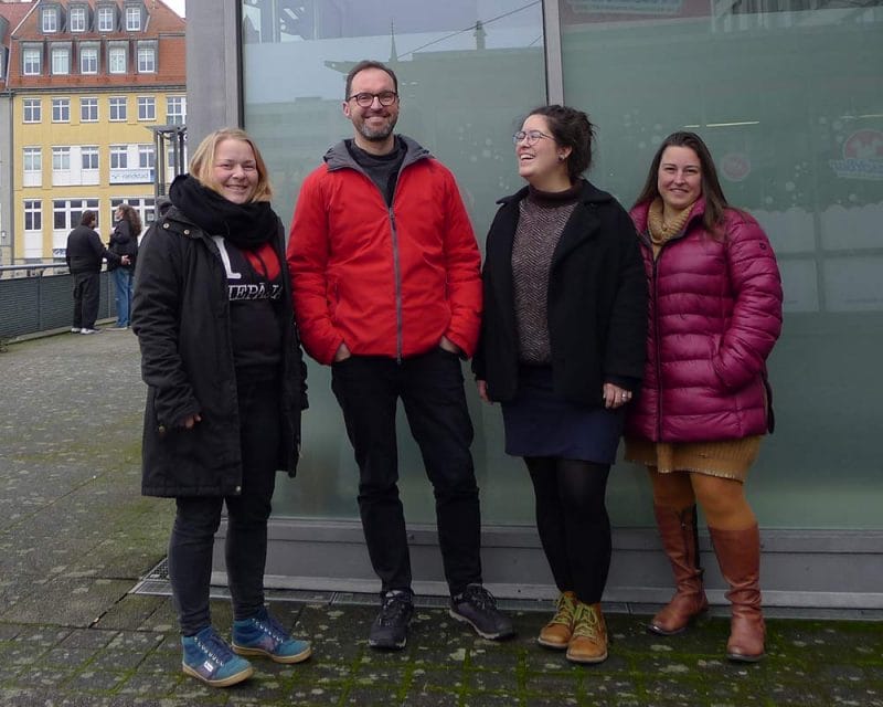 Vier Personen stehen vor einer Glaswand