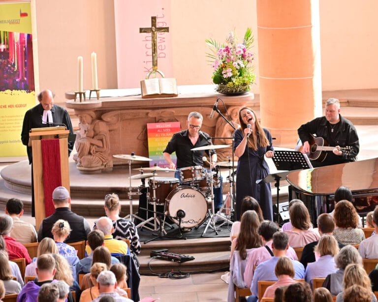 Eine Band spielt vor einem Altar im Kirchsaal ein Konzert