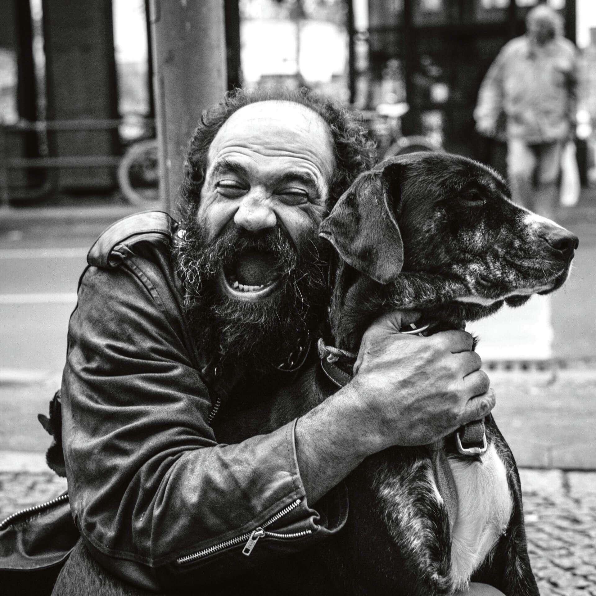 Mann mit offenen Mund, der einen Hund umarmt.