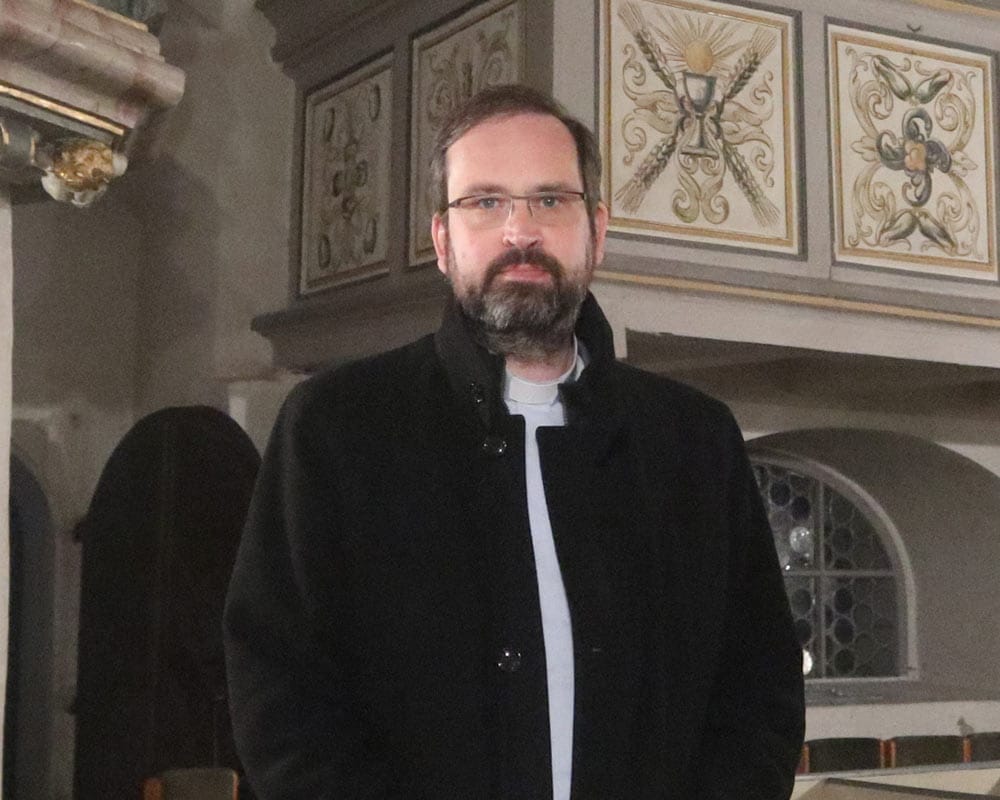 Pfarrer mit Brille und Bart in einer Kirche