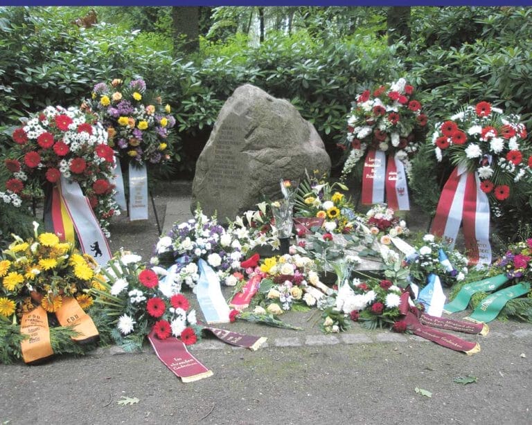 Gedenkstein mit vielen Blumenkränzen