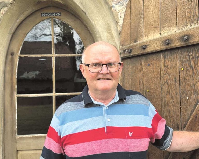 Mann mit Brille und gestreiftem Hemd vor einer Tür