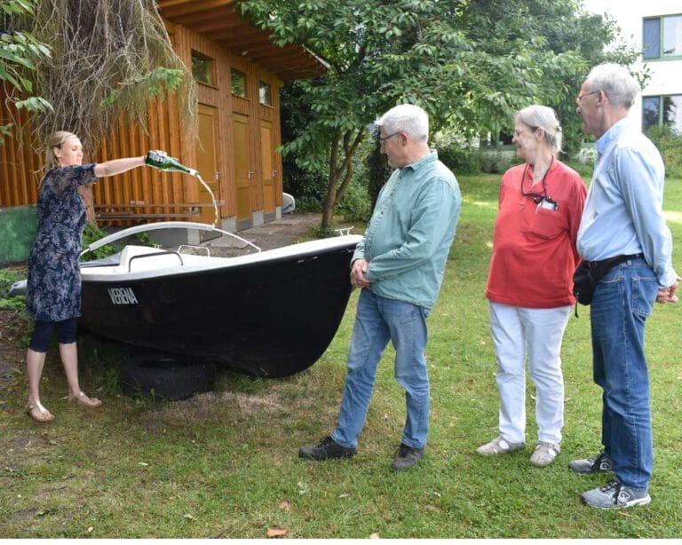 Frau begiesst ein Boot aus einer Flasche