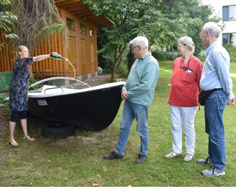 Frau begiesst ein Boot aus einer Flasche
