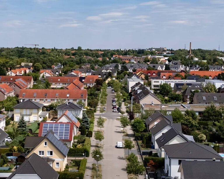 Häusersiedlung mit Straße in der Mitte und blauem Himmel im Hintergrund
