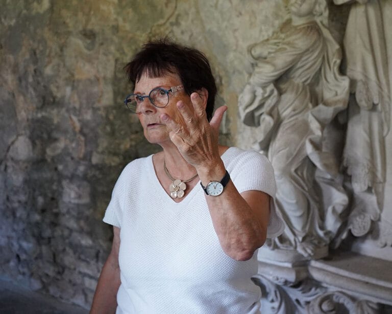 Frau in weißem T-Shirt vor einer Statue