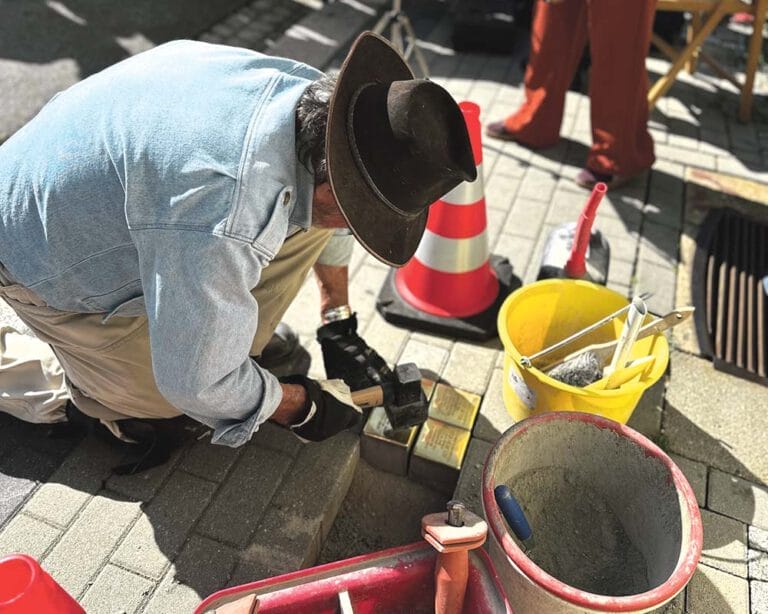 Mann mit Hut verlegt Stolpersteine