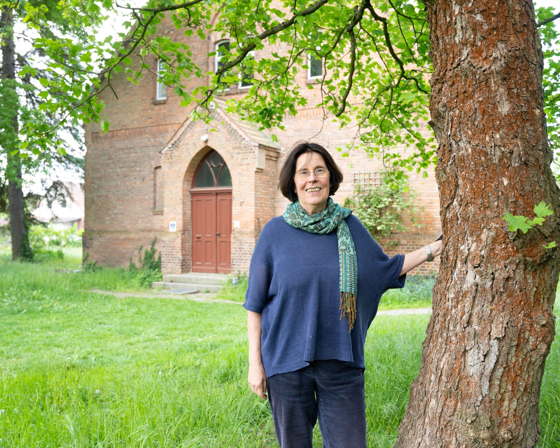 Frau auf einer Wiese vor einem Haus