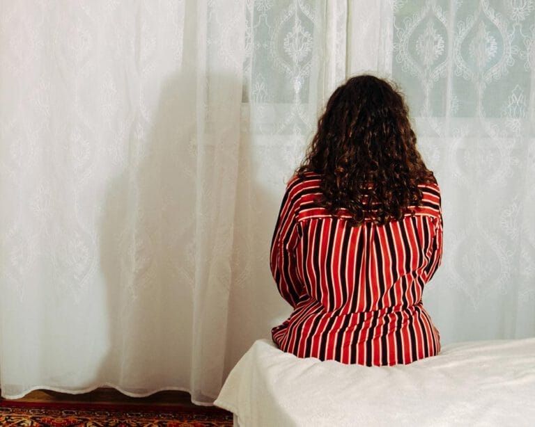 Frau sitzt auf Bett