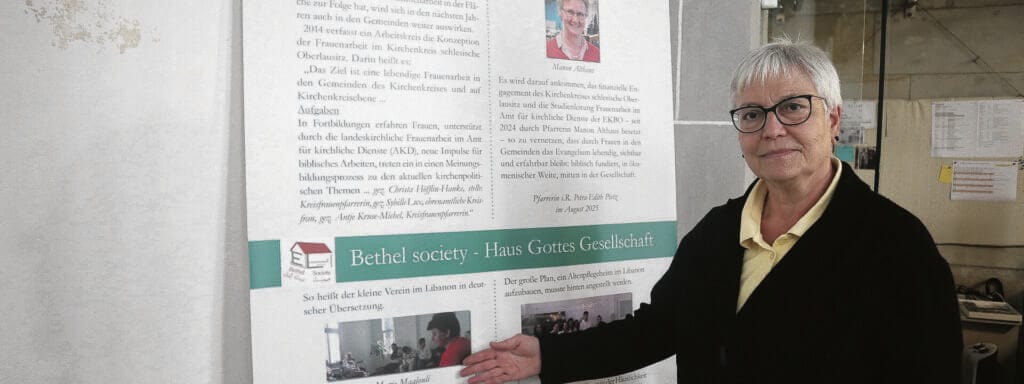Frau mit grauen Haaren vor einer Schautafel