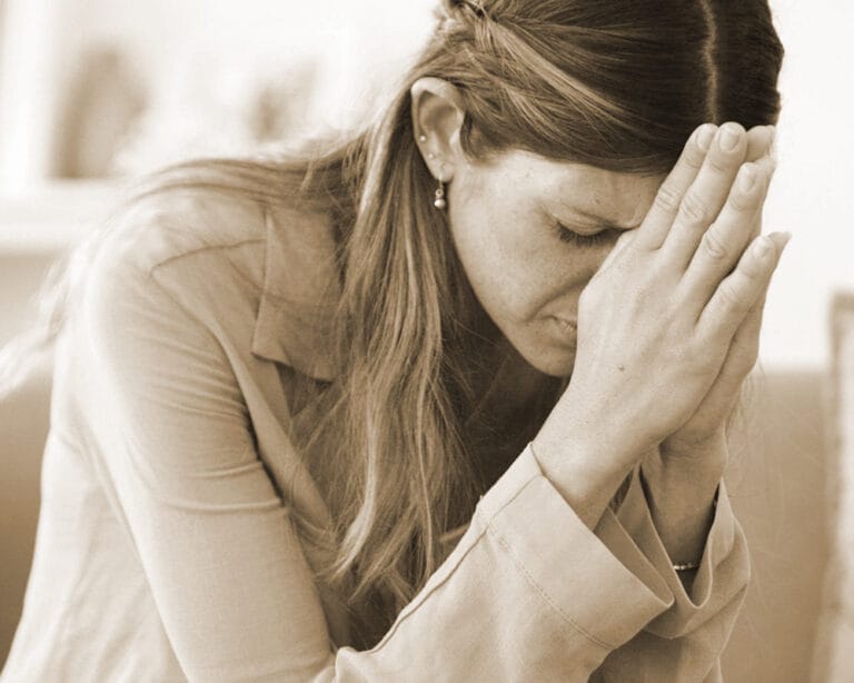 Verzweifelt betende Frau mit gefalteten Händen