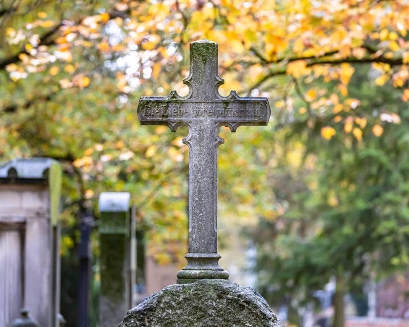 Kreuzförmiger Grabstein auf einem Friedhof
