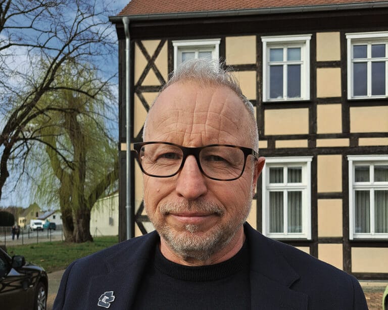 Mann vor einem Fachwerkhaus