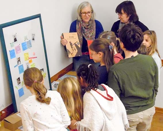 Kinder mit Erwachsenen an einer Bildtafel