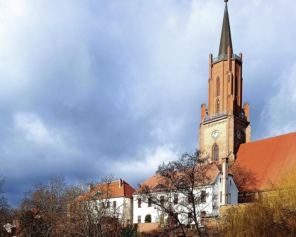 Kirchturm vor blauem Wolkenhimmel